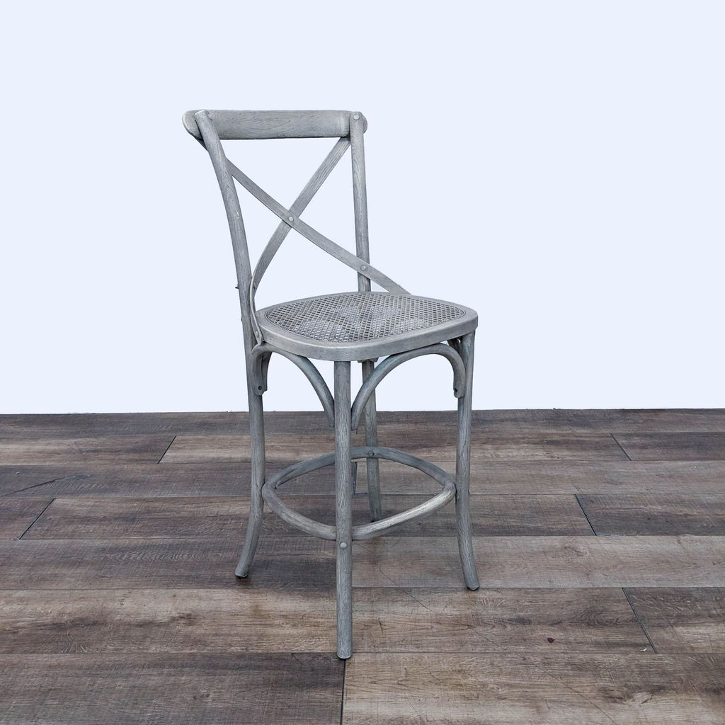 Side view of a grey barstool featuring a woven seat and cross-back design.