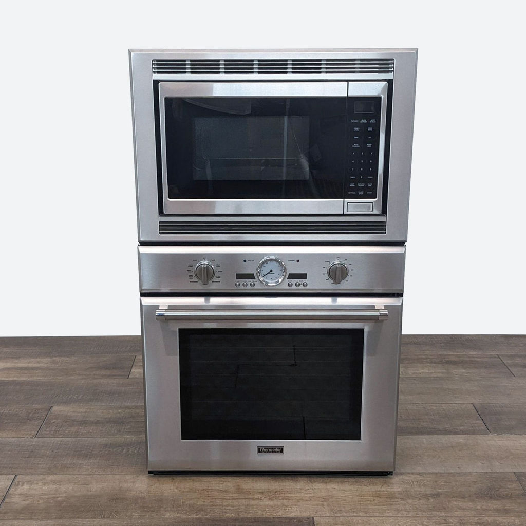 a stainless steel oven and microwave on a wooden floor.