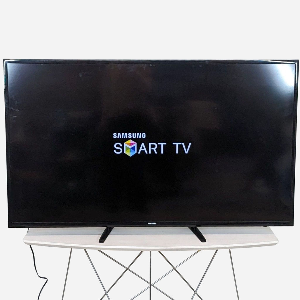 a samsung smart tv on a stand with a samsung logo on it.