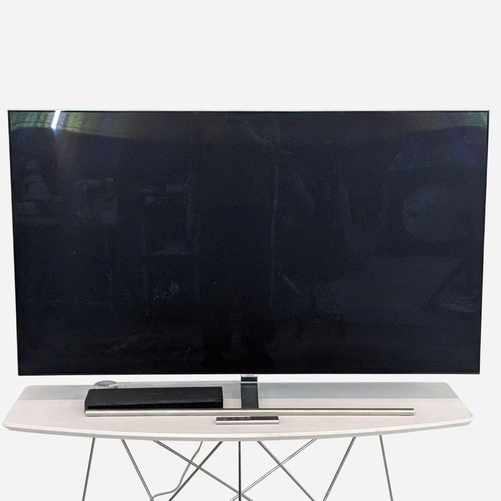 Samsung 55-inch QLED TV with a soundbar on a sleek stand.