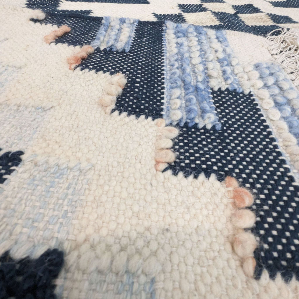 Close-up of chunky, looped wool and raised stitching on a blue and white pattern.