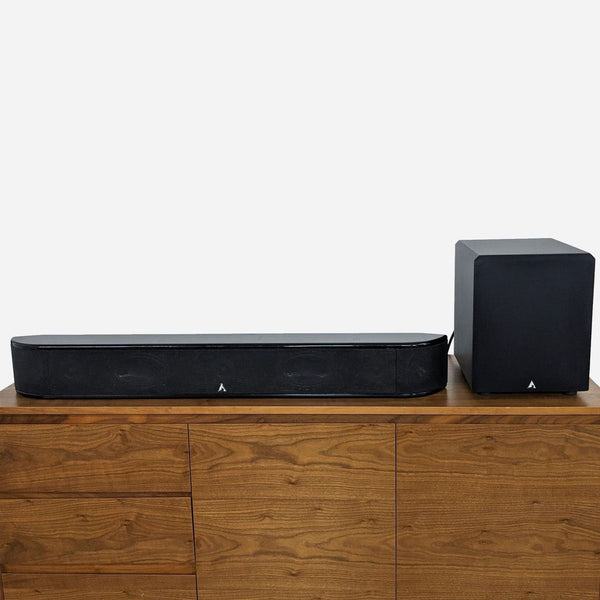 a pair of black subwoofers on a wooden table