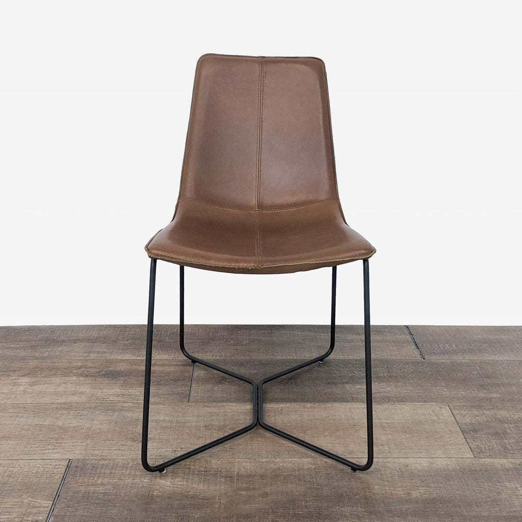 Front view of a brown leather dining chair with metal legs on a wood floor.