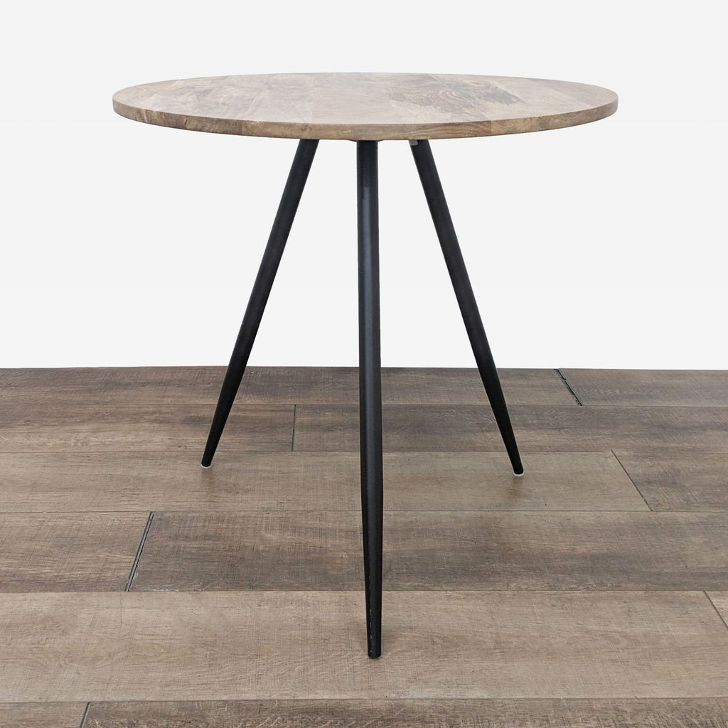 Round mango wood table with iron tripod base by West Elm.