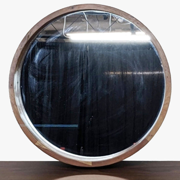 Round mirror from CB2 with an acacia wood frame, shown from the front, reflecting a dark background.
