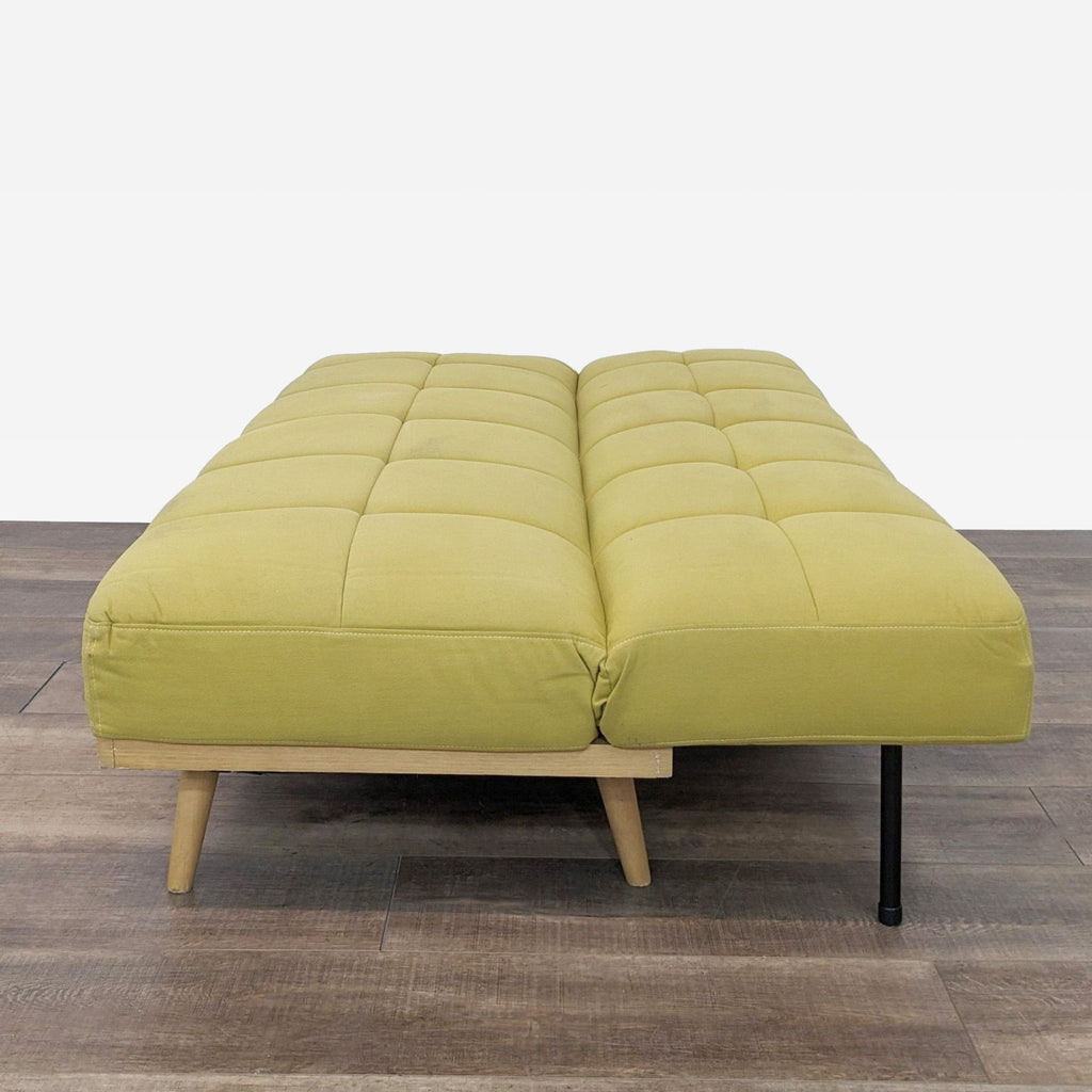 a green sofa with a black metal frame and a wooden base.