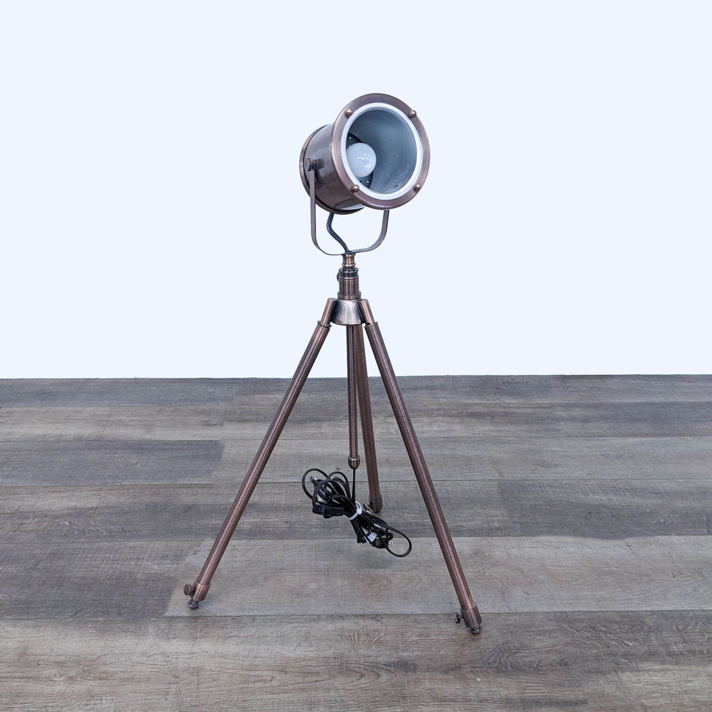 Industrial-style tripod lamp with a spotlight design in bronze finish.