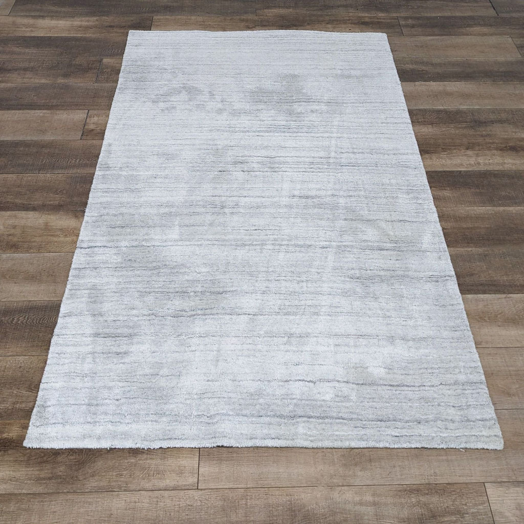 Shale Striations 5x8 Rug by West Elm on wooden floor, featuring a subtle striped pattern.