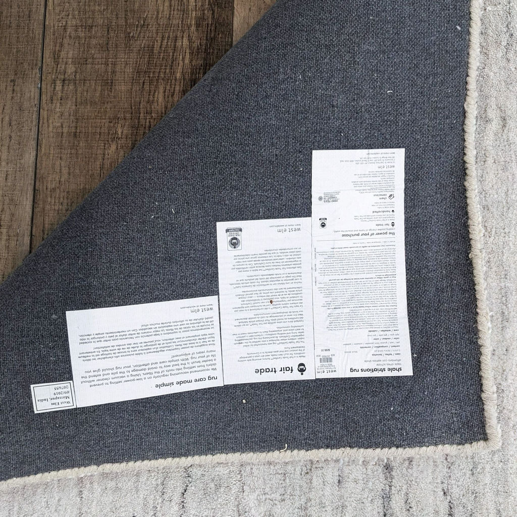 Underside of the Shale Striations Rug showing labels and detailed craftsmanship on a wooden floor.