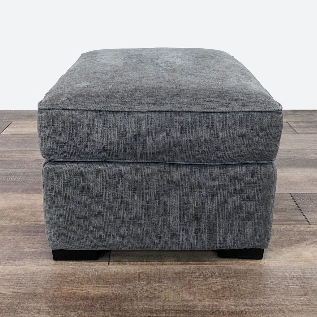 a grey velvet ottoman with a square foot foot.