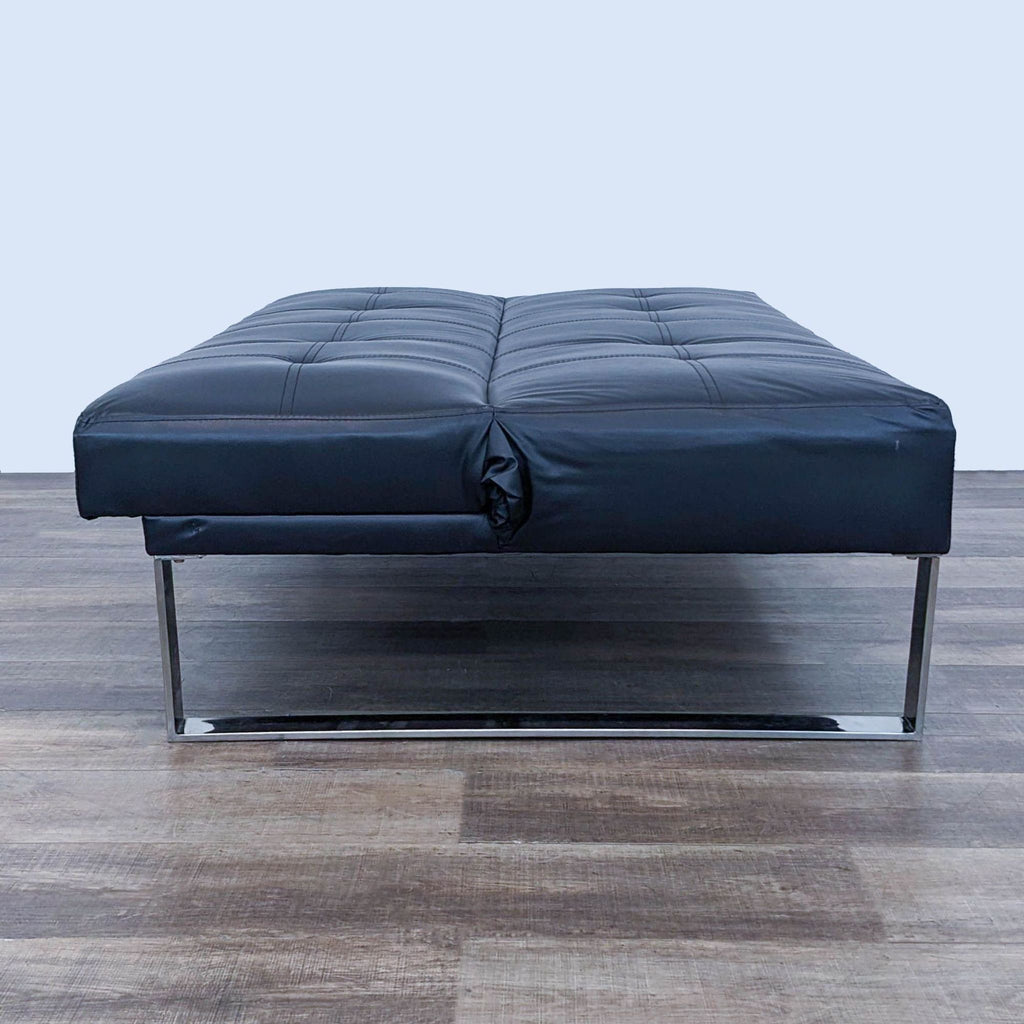 a black leather ottoman with chrome legs and a chrome frame.