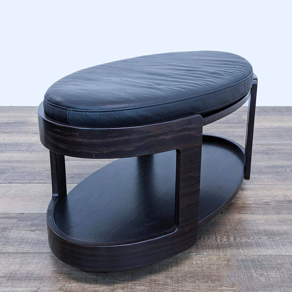 a black leather footstool with a black leather seat.