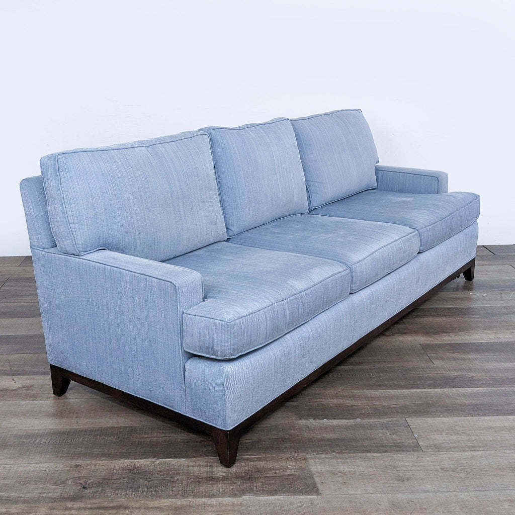 Angled view of the Cypress contemporary 3-seat sofa with blue upholstery and wooden base.