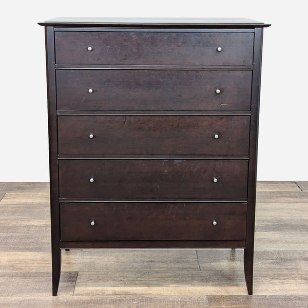 a dark brown chest of drawers with metal knobs.