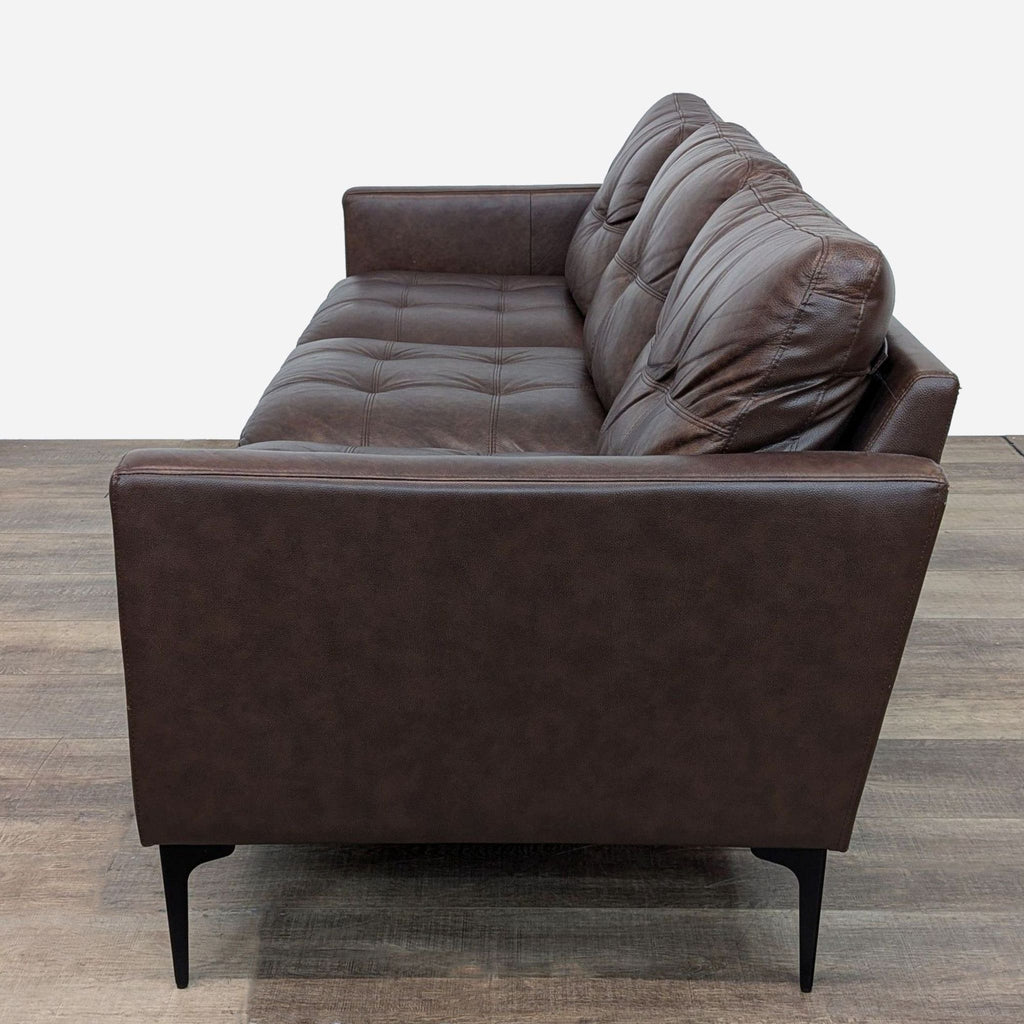 a brown leather sofa with a black base and a brown cushion.