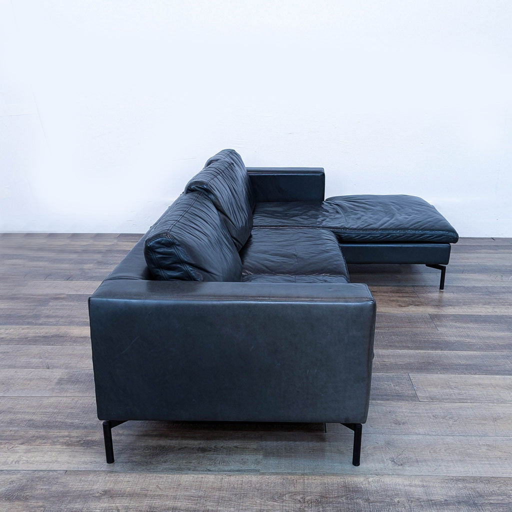 a pair of black leather sofas and a black leather ottoman