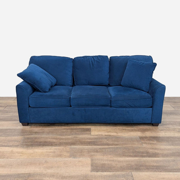 a blue sofa in a room with a wooden floor.