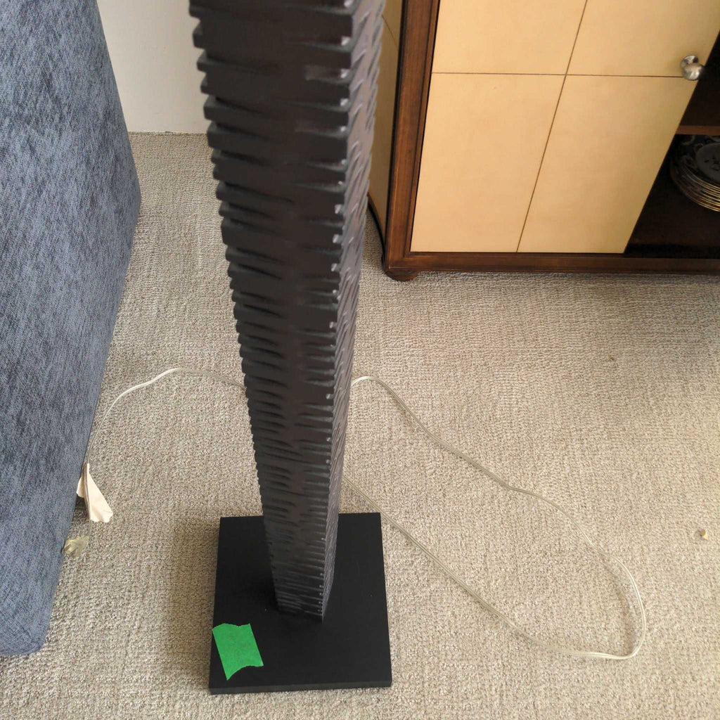 1. Modern floor lamp with a textured dark base and square pedestal, placed on a light carpet near furniture.