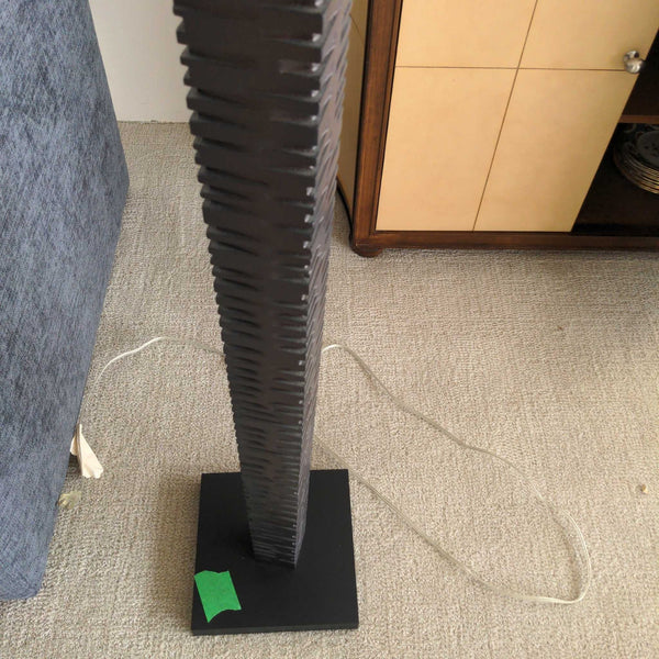 1. Modern floor lamp with a textured dark base and square pedestal, placed on a light carpet near furniture.
