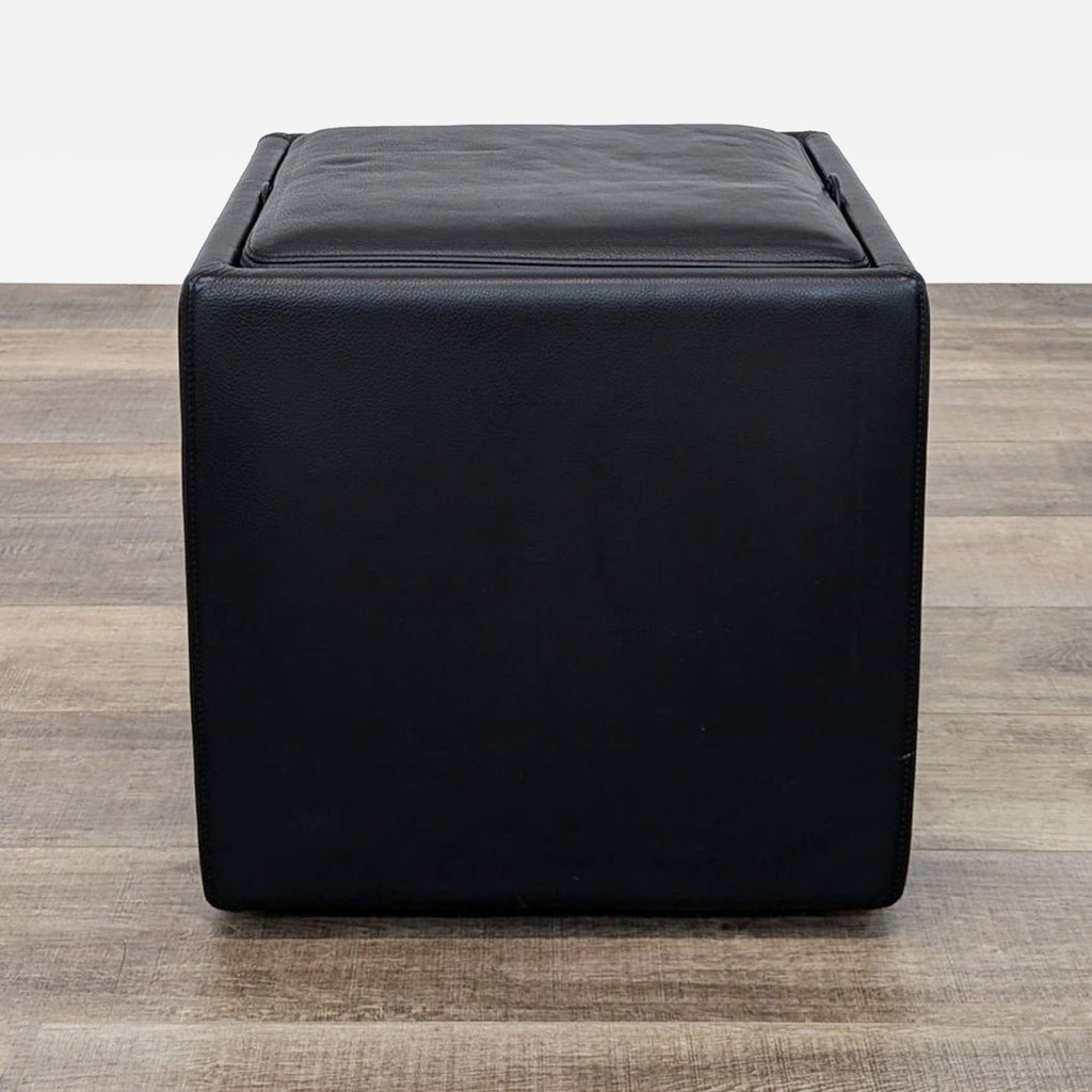 the ottoman is made of leather and features a square leather base.
