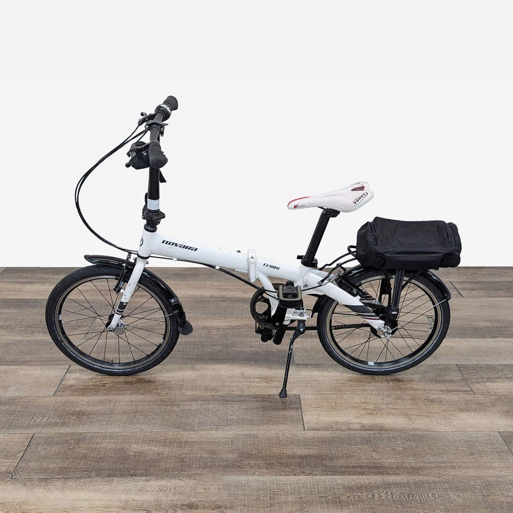 a white folding bike with a black bag on the seat.