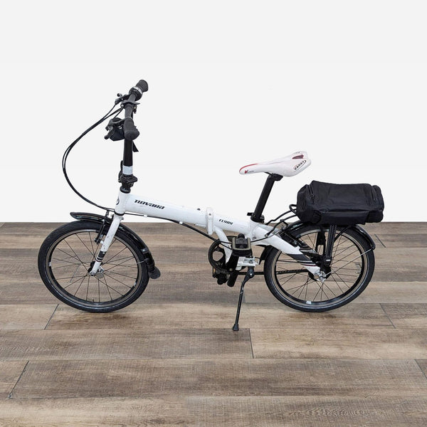 a white folding bike with a black bag on the seat.