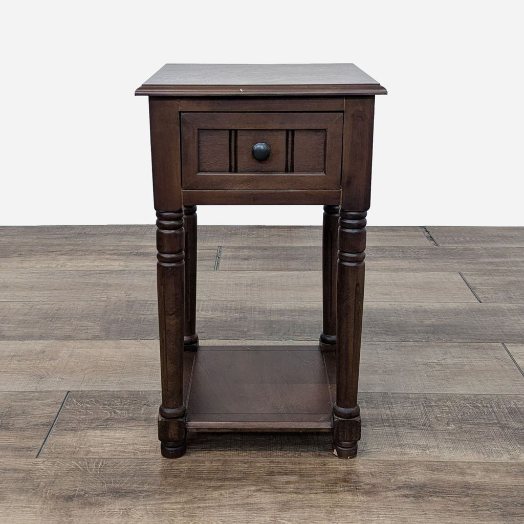 a dark brown wood bedside table with a black drawer and a small drawer.