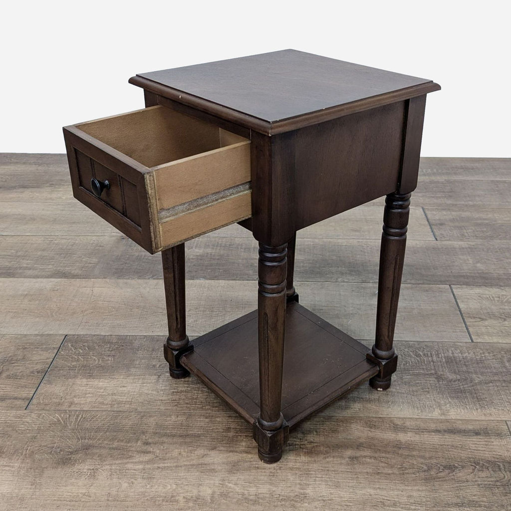 a small, dark wood bedside table with a drawer.