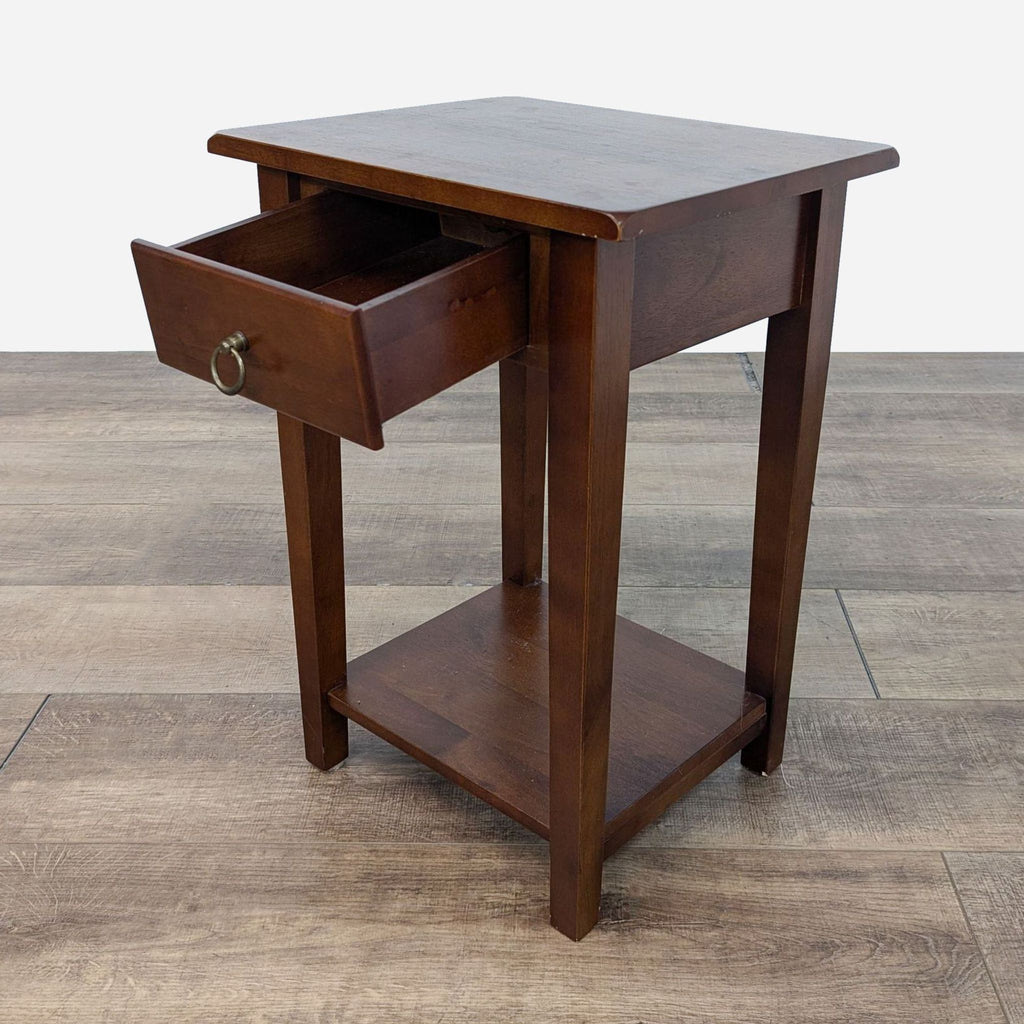 a small, dark wood bedside table with a drawer.