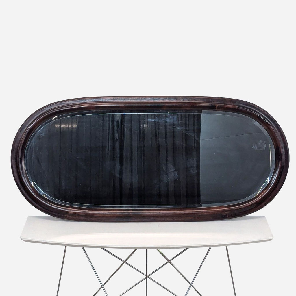 a large oval mirror with a dark brown frame and a white metal base.