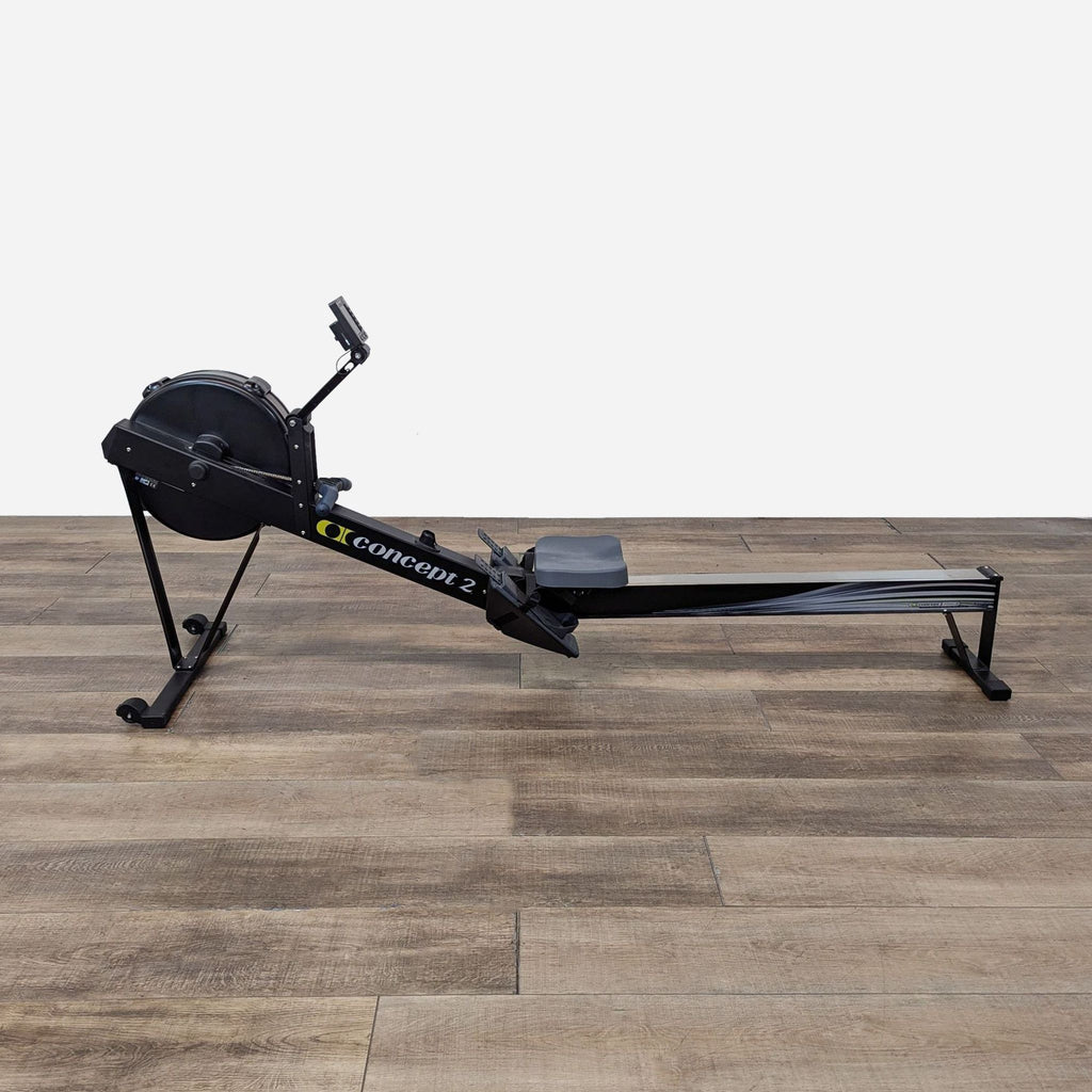 a black rowing machine on a wooden floor.