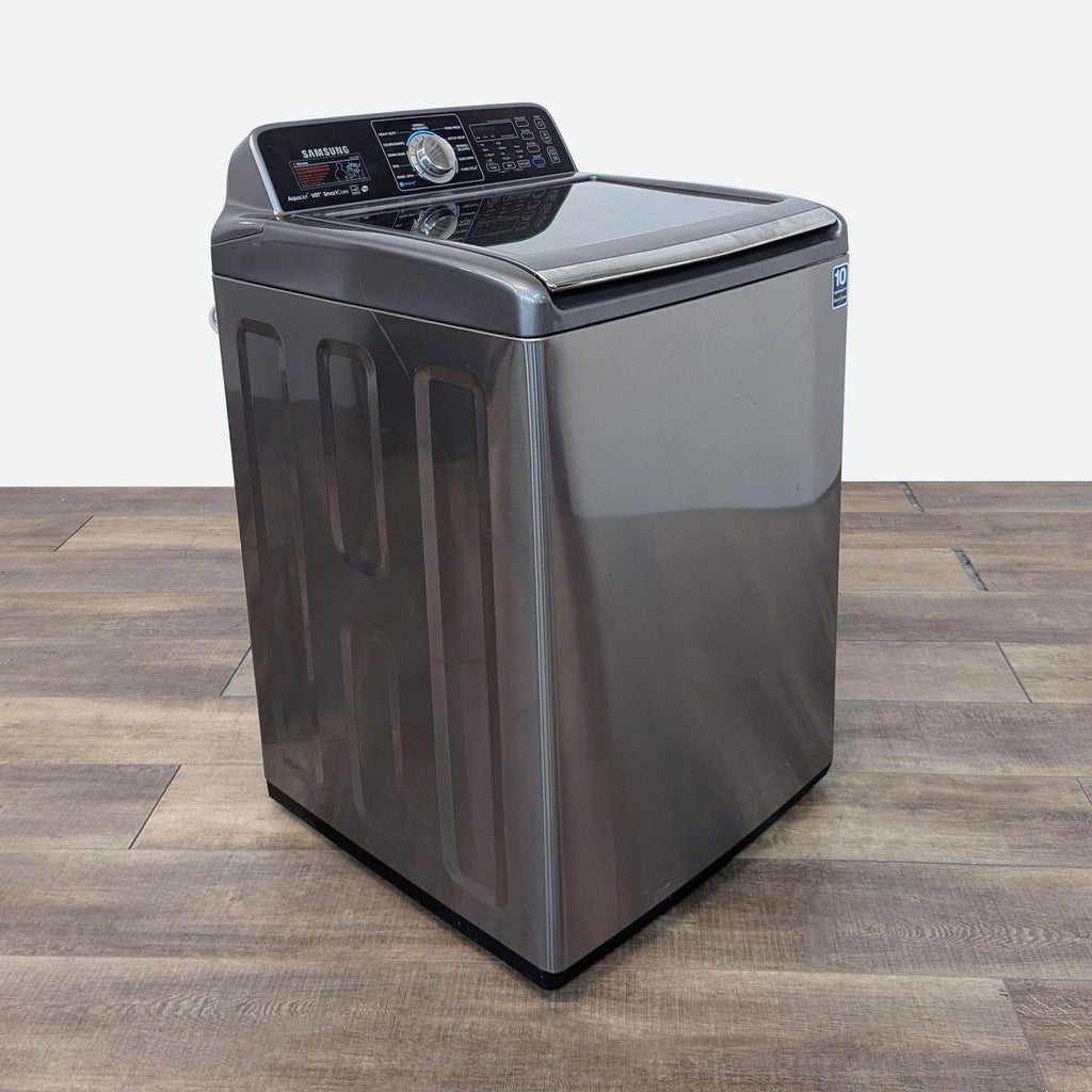 a photo of a silver washing machine on a wooden floor.