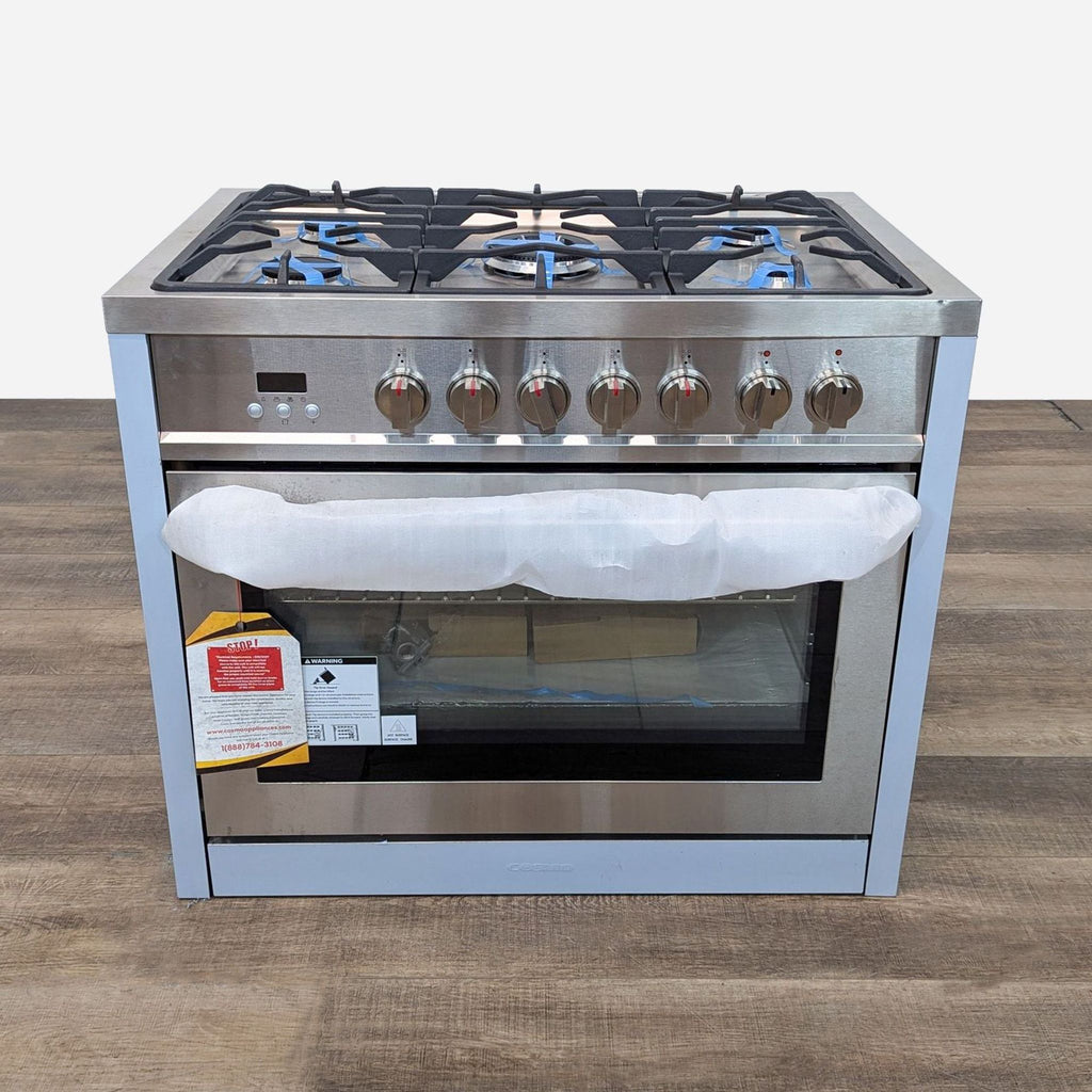 a stainless steel stove with four burners on a wooden table.