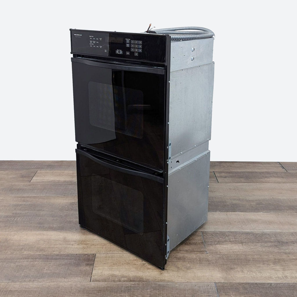 a black dishwasher with a white dishwasher on a wooden floor.