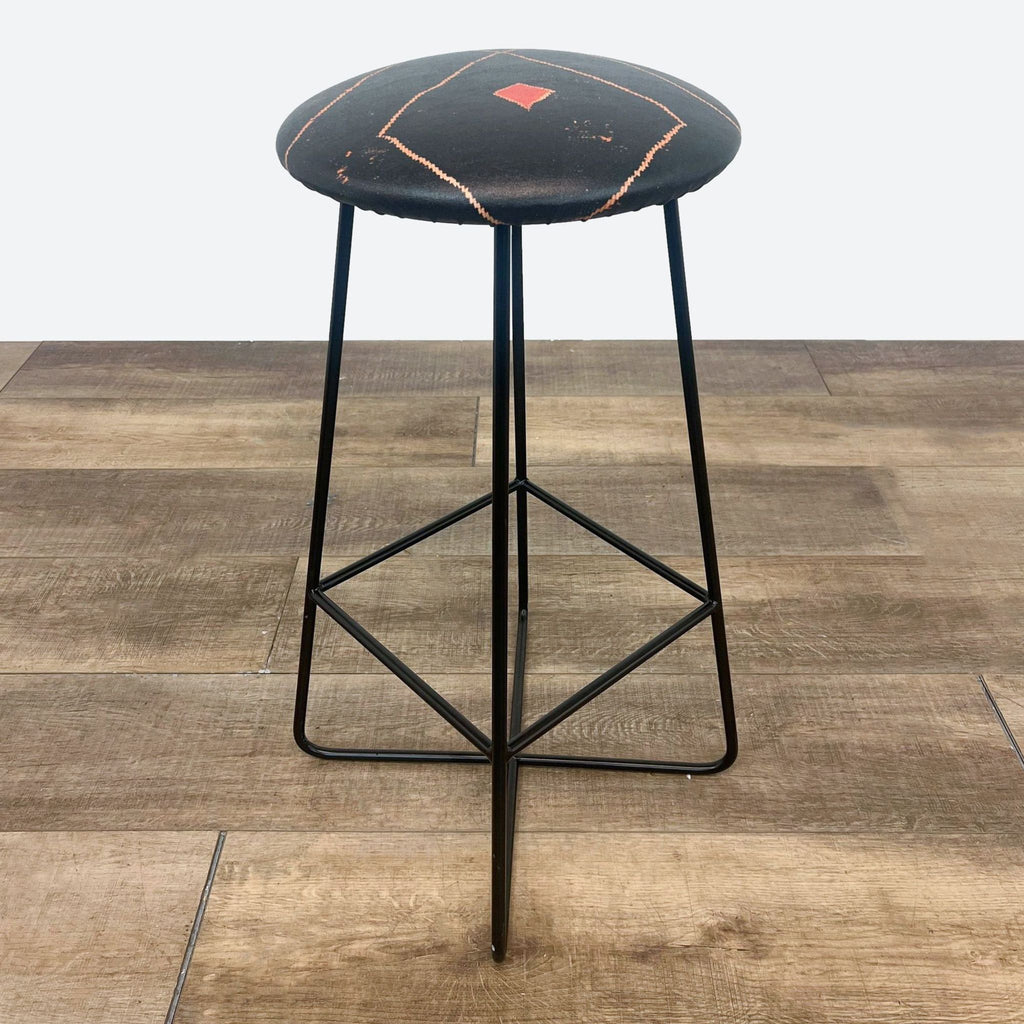 the stool is made of a black metal with a red diamond on the back.