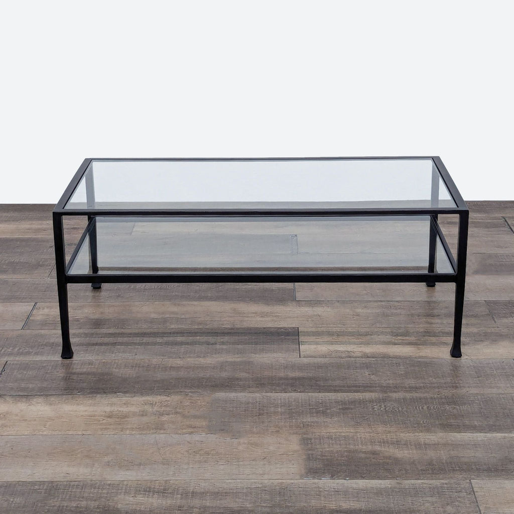 Glass-top coffee table with black metal frame and lower shelf by Crate & Barrel.