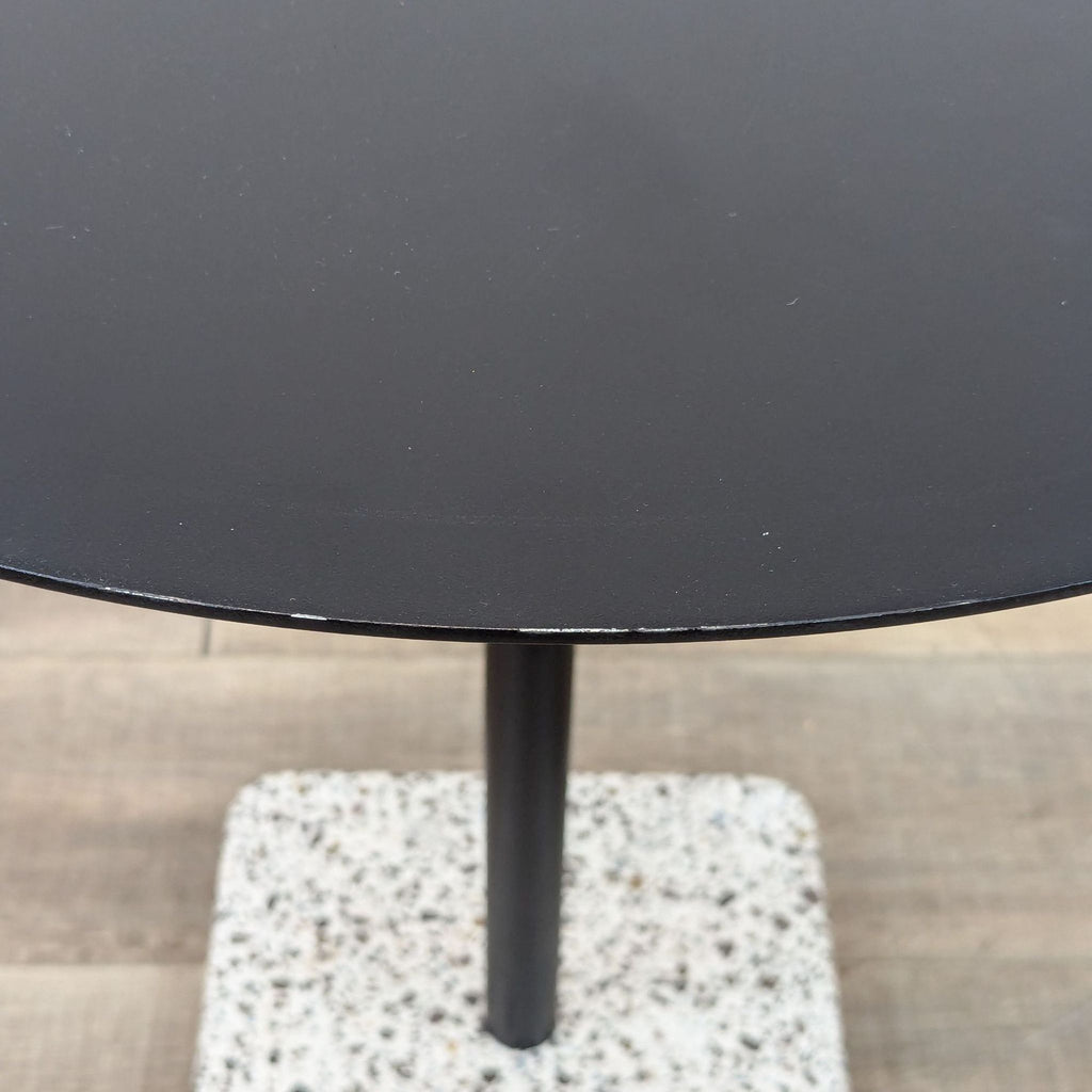 a pair of black round table with a black metal base.