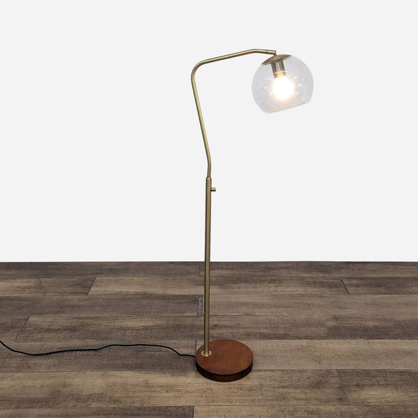 a brass floor lamp with a glass globe.