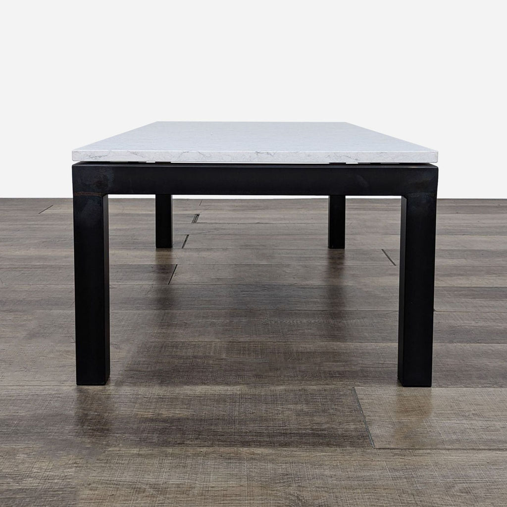 Close-up front view of a Reperch coffee table, showcasing its metal base and sleek, light-colored top.