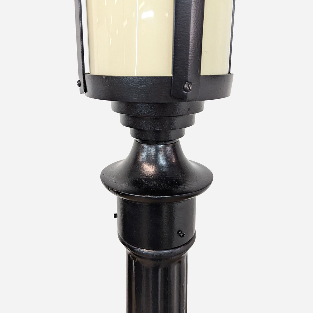 a black cast iron street light with a white glass shade.