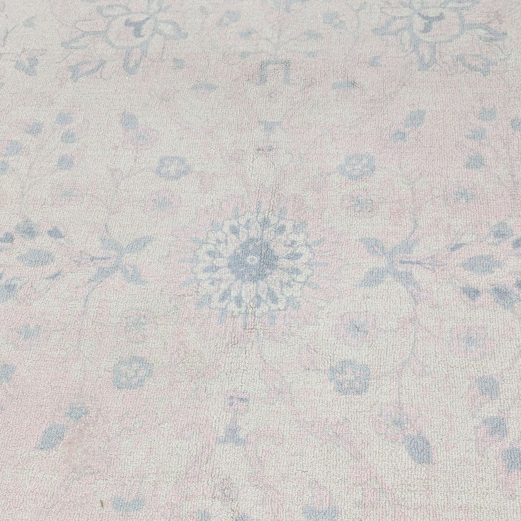 Close-up of central floral pattern on a blush pink handwoven rug, emphasizing intricate details.