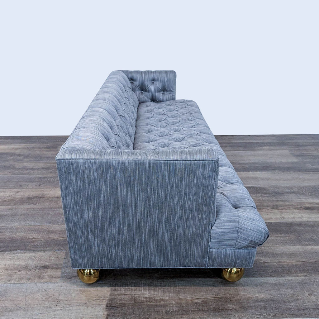 2. Side view of Jonathan Adler 3-seat sofa showcasing its tufted blue-gray upholstery and brass legs.