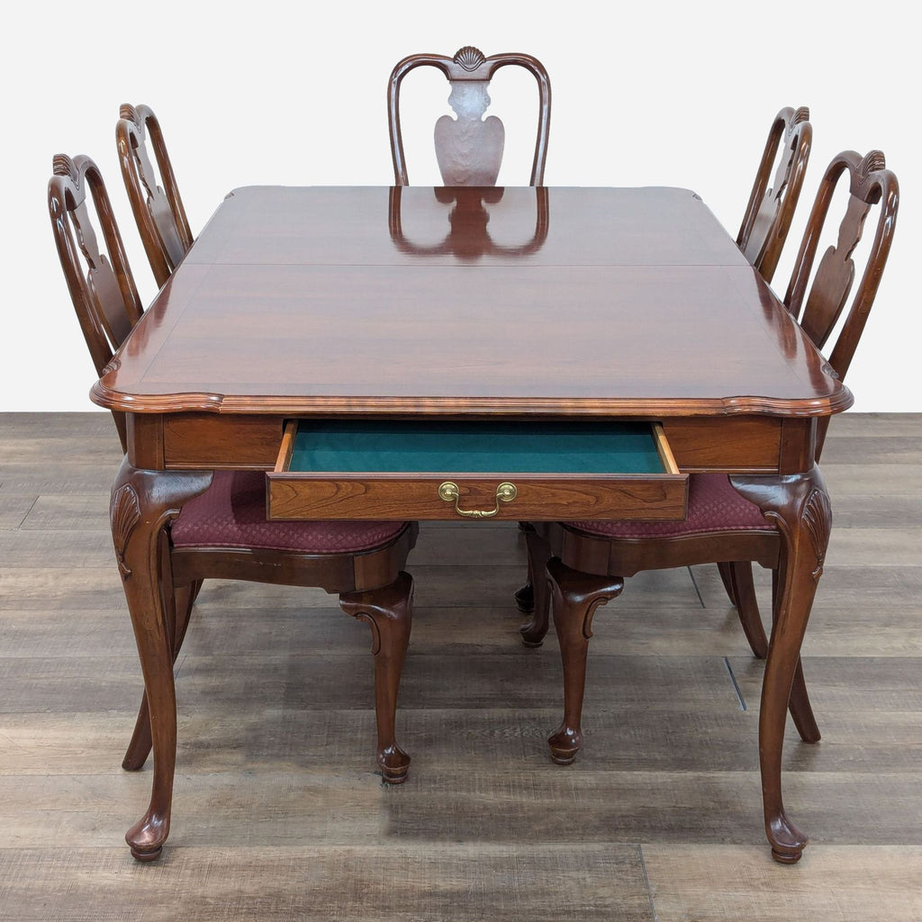 a dining table with four chairs and a table with a drawer.