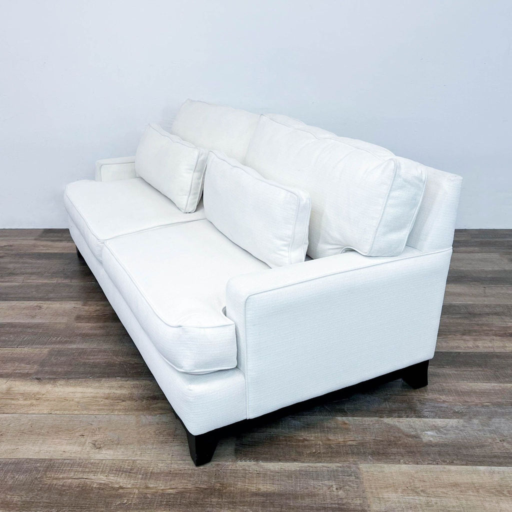 a white leather sofa with a white leather back and two white pillows.