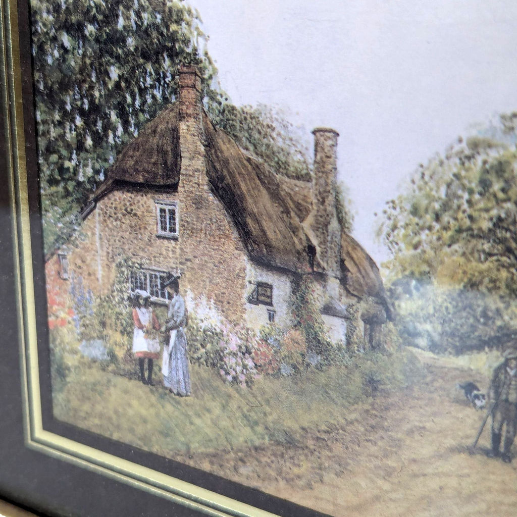 a framed print of a couple standing in front of a thatched cottage.