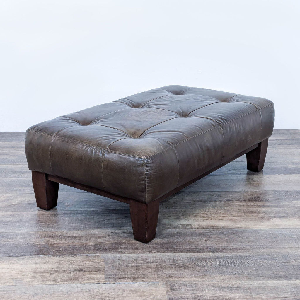 a brown leather tufted ottoman with a buttoned up tufted seat.