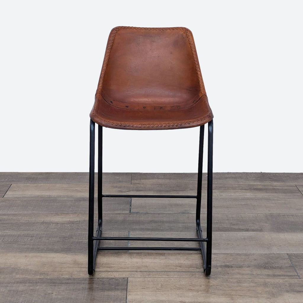 a brown leather bar stool with a black metal frame.