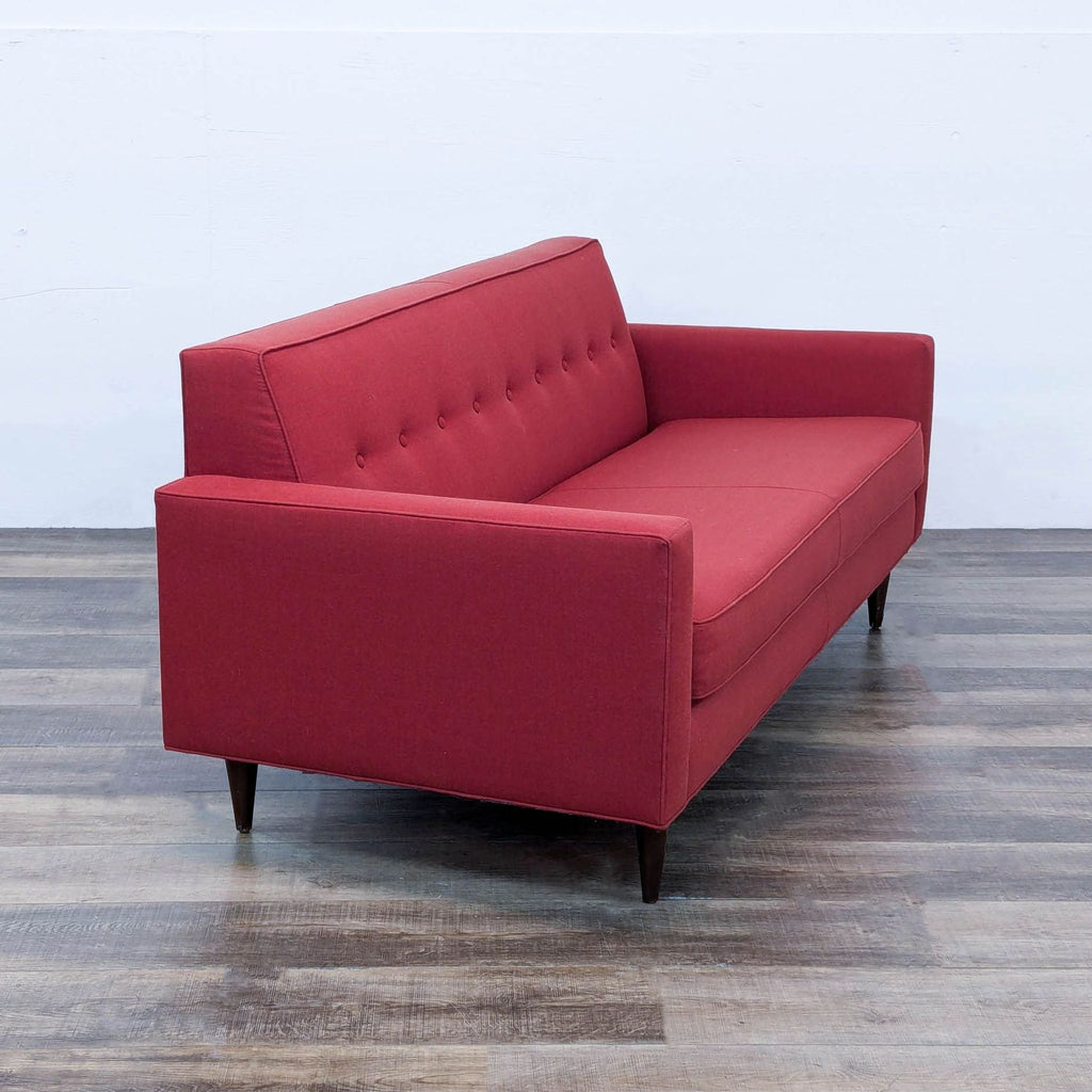 a red sofa with a tufted back and a tufted back.