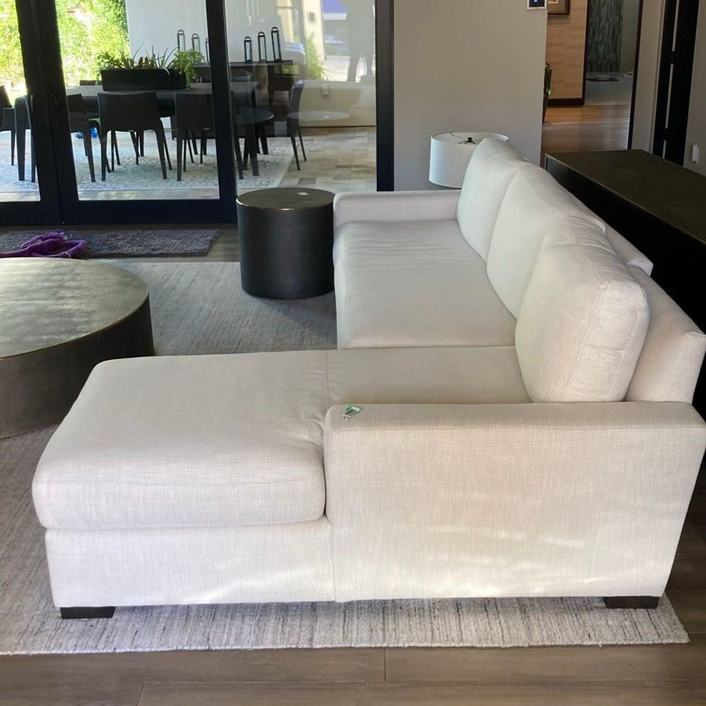 2. Side view of a cream Restoration Hardware sectional with chaise, featuring clean lines on a light area rug.
