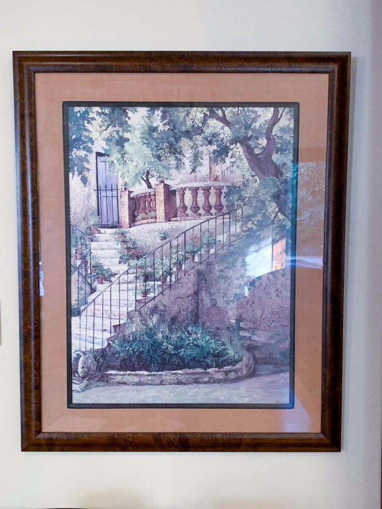 a framed painting of a house and a gate.